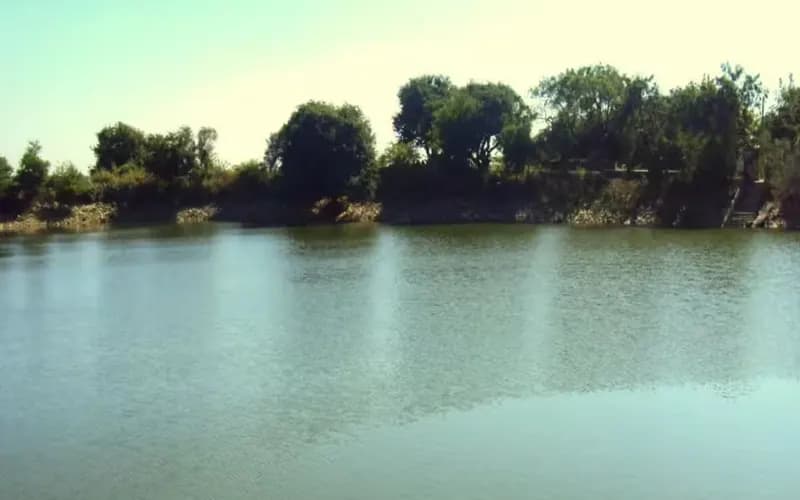 The still water and wooded bank of Gopi Talav