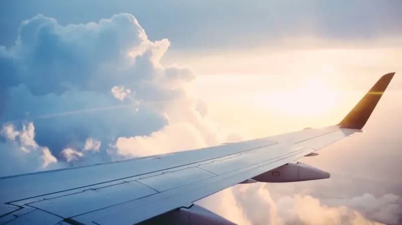 Aircraft wing above the clouds at sunset